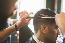Парикмахер-мужчина стрижет клиента в парикмахерской — стоковое фото
