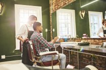 Homme coiffeur et client avec tablette numérique parler dans le salon de coiffure — Photo de stock