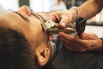 Fechar o homem recebendo uma barba na barbearia — Fotografia de Stock