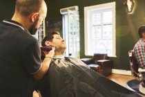 Hombre recibiendo un afeitado en la peluquería - foto de stock