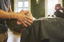 Masculino barbería masajear cara de cliente en la barbería - foto de stock