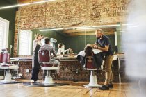 Barbeiros masculinos e clientes em barbearia — Fotografia de Stock