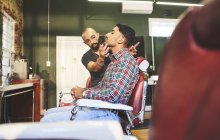 Male barber and customer in barbershop — Stock Photo