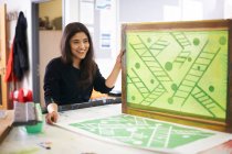 Smiling female art student screen printing in art studio — Stock Photo
