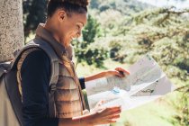 Young female hiker looking at trail map in sunny woods — Stock Photo