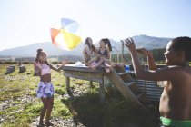 Verspieltes lesbisches Paar und Kinder mit Strandball am abgelegenen, sonnigen Sommerpool — Stockfoto