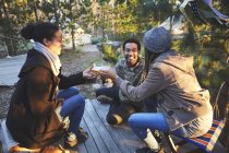 Happy friends drinking wine at campsite in woods — Stock Photo