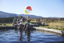 Porträt des verspielten Geschwisterpaares mit Strandball am sonnigen, sommerlichen Pool — Stockfoto