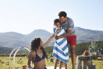 Familia feliz, cariñosa en remoto, soleado, junto a la piscina de verano - foto de stock