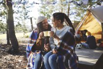 Feliz pareja lesbiana relajándose, tomando café en el camping soleado - foto de stock