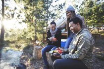 Glückliche Freunde essen auf sonnigem Campingplatz — Stockfoto