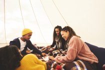 Feliz pareja de lesbianas y niños jugando a las cartas en la yurta de camping - foto de stock