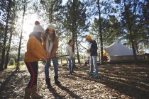 Coppia lesbica e bambini che raccolgono legna da ardere accesa nel campeggio soleggiato nel bosco — Foto stock