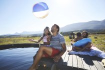 Playful family with beach ball at sunny, summer swimming pool — Stock Photo