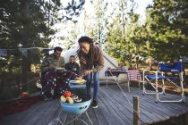 Family cooking vegetables at campsite grill in woods — Stock Photo