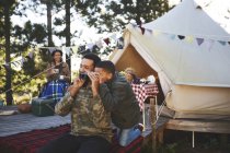 Curioso pai e filho usando binóculos fora yurt no acampamento — Fotografia de Stock
