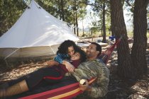 Feliz, família despreocupada relaxando em rede no acampamento na floresta — Fotografia de Stock