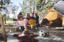 Casal de lésbicas e crianças comendo na mesa de piquenique fora yurt no acampamento ensolarado — Fotografia de Stock