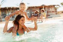 Mother and daughter playing in sunny ocean — Stock Photo
