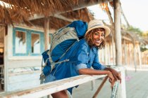 Portrait happy young female backpacker on beach hut patio — Stock Photo
