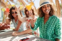 Portrait happy women friends with cocktails at sunny beach bar — Stock Photo