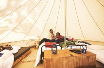Feliz, família despreocupada relaxando na cama no acampamento yurt — Fotografia de Stock