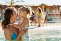 Happy, affectionate mother and daughter swimming in sunny ocean — Stock Photo