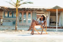 Heitere junge Frau im Bikini sonnt sich am sonnigen Strand — Stockfoto