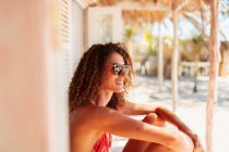 Щаслива, безтурботна молода жінка розслабляється на сонячному пляжі хатинка патіо — стокове фото