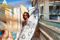 Ritratto giovane donna con tavola da surf sulla spiaggia soleggiata — Foto stock