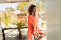 Serene young woman relaxing on sunny beach hut patio — Stock Photo