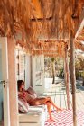 Jovem mulher de biquíni relaxante na praia ensolarada cabana pátio — Fotografia de Stock