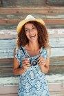 Portrait happy, carefree young woman with retro camera against wood plank wall — Stock Photo