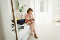 Жінка пише в журналі поруч з валізою на пляжній хатинці спальні — стокове фото