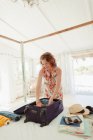 Donna disimballaggio valigia in spiaggia capanna camera da letto — Foto stock
