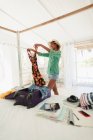 Счастливая женщина распаковывает чемодан в спальне пляжного дома — стоковое фото