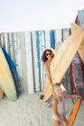Retrato mãe feliz e filha com prancha de surf na praia ensolarada — Fotografia de Stock