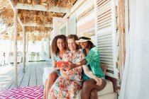 Mãe feliz e filhas adultas tomando selfie no pátio da cabana de praia — Fotografia de Stock