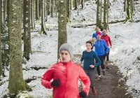 Amigos corriendo en bosques nevados - foto de stock