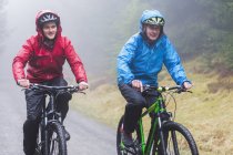 Отец и сын катаются на горном велосипеде под дождем — стоковое фото