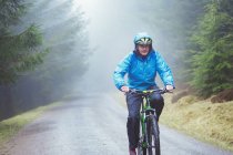 Senior man mountain biking in woods — Stock Photo