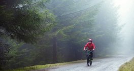 Man mountain biking in rain — Stock Photo