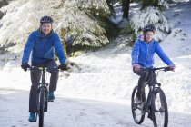 Pareja de ciclismo de montaña en bosques nevados - foto de stock