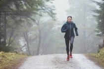 Woman jogging in rainy woods — Stock Photo