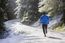 Homme jogging dans les bois enneigés — Photo de stock