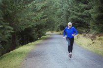 Senior man jogging in woods — Stock Photo