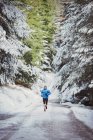 Man jogging in snowy woods — Stock Photo