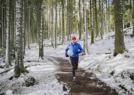 Senior man jogging in snowy woods — Stock Photo