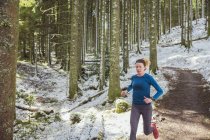 Woman jogging in snowy woods — Stock Photo
