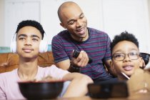 Padre e hijos comiendo y viendo la televisión - foto de stock